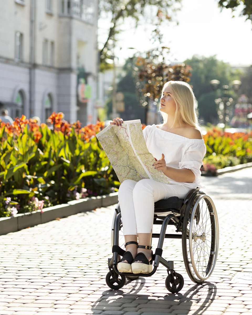 Mulher em cadeira de rodas consultando um mapa em uma rua florida — cadeira de rodas portátil para viagem em Vinhedo